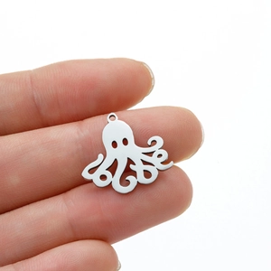 Macro detail of a small stainless steel octopus pendant held between fingers for size reference