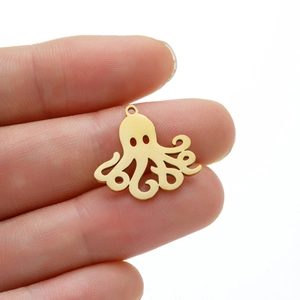 Golden octopus charms in stainless steel shown on hand to demonstrate mini size