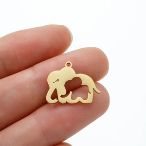 Pendentif éléphant doré avec motif évidé tenu à la main pour montrer la taille réelle