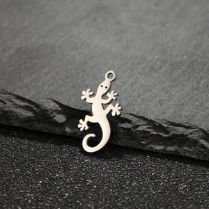 Detailed view of silver stainless steel lizard charms on dark stone texture background