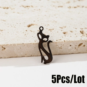 Macro detail of five black stainless steel cat silhouette charms on a textured stone surface