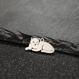Macro shot of cute lying cat pendant in silver stainless steel on textured stone background