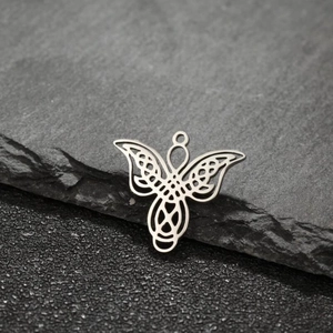 Detailed close-up of a silver polished stainless steel Celtic knot angel pendant on stone