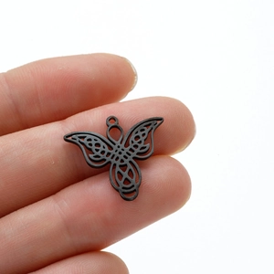 Macro shot of matte black hollow butterfly pendant with Celtic knot pattern detail