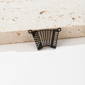 Detailed view of accordion charm with black finish and hollow craftsmanship on stone pedestal