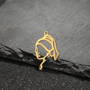 Macro shot of gold Girl with a Pearl Earring metal charm on grey stone texture