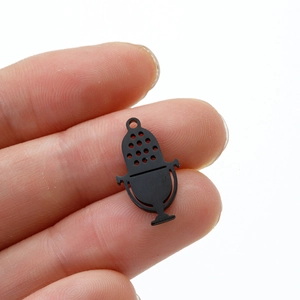 Macro shot of a mini matte black microphone pendant held by hand for DIY jewelry making