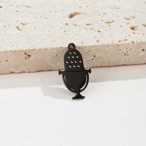 Macro shot of vintage matte black stainless steel microphone pendant on stone background