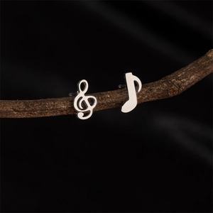 Minimalist silver music note earrings for women in stainless steel on wood branch