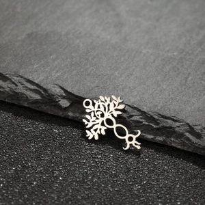 Close-up of vintage Tree of Life stainless steel pendants on a textured grey stone surface