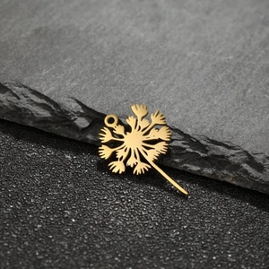 Detailed view of a gold dandelion flower pendant accessory on a dark textured rock