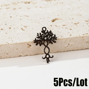 Detailed view of 5 black stainless steel Tree of Life pendants on a stone surface
