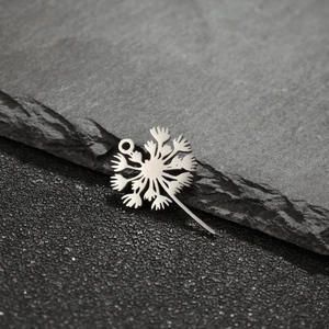 Macro shot of silver dandelion pendant with hollow cut-out design on stone background