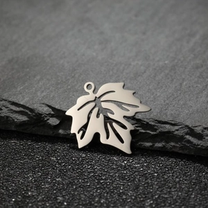 Vue détaillée du pendentif feuille d'érable ajouré sur une surface en pierre sombre