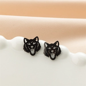 Detailed close-up of a vintage black wolf head stud earring on a white ceramic tray