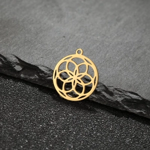 Gros plan d'un pendentif fleur géométrique plaqué or 18 carats sur pierre sombre