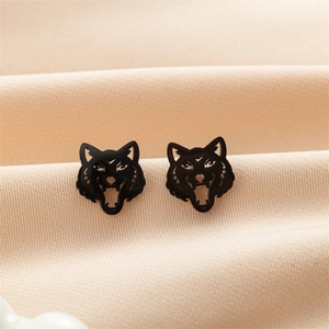 Detailed view of black wolf head stud earrings featuring hollow punk style on satin fabric