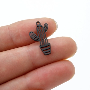 Macro shot of a black cactus pendant with hollow details held between fingers