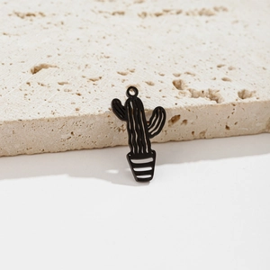Detailed view of a black cactus pendant with gold-plated loop on a beige stone slab