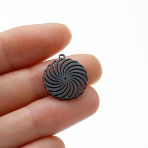Detail of matte black stainless steel geometric spiral flower pendant held for size scale