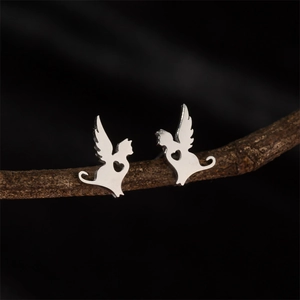 Détail de boucles d'oreilles chat avec ailes et cœur ajouré sur une branche en bois