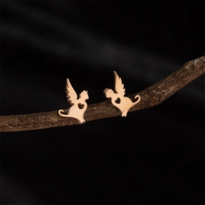 Gros plan de boucles d'oreilles chat aile rose doré avec cœur sur branche boisée
