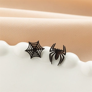 Macro shot of gothic black spider and web mismatched stud earrings on a ceramic tray