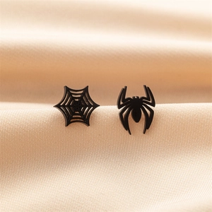 Detail of matte black gothic spider and web stud earrings on beige satin fabric