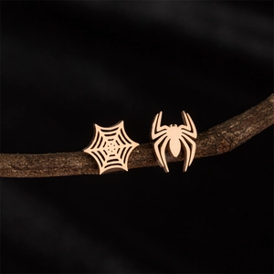 Asymmetric rose gold spider and web stud earrings in stainless steel on wood