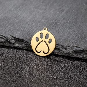 Macro view of a gold-plated heart paw print hollow pendant on dark stone surface