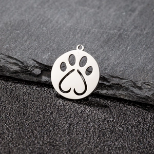 Macro shot of silver stainless steel circular charm with cutout paw print and heart