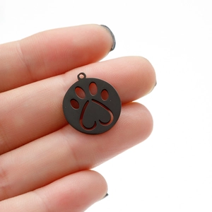 Detail of a small matte black stainless steel charm with a cute hollow cat paw print design