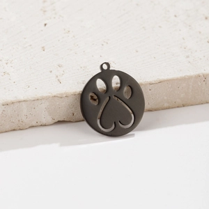 Detailed view of a black matte paw print heart cutout pendant on a textured stone