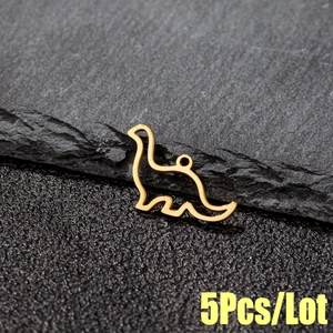 Macro view of 5 golden stainless steel hollow dinosaur charms on a dark stone background