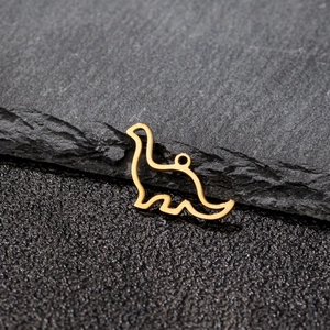 Close-up of golden stainless steel hollow dinosaur charm on black stone texture