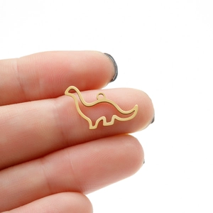 Close-up of a small hollow gold dinosaur pendant held to show actual size and detail