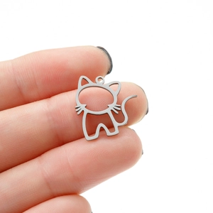 Gros plan d'un pendentif chat évidé en acier inoxydable argenté entre les doigts
