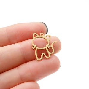Gros plan d'un petit pendentif chat doré en acier inoxydable tenu pour l'échelle de taille