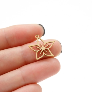 Macro detail of gold hollow star flower pendant held to show small size