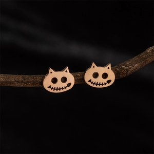 Gothic rose gold stainless steel cat stud earrings displayed on a rustic branch