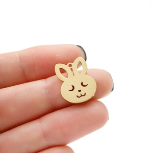 Detailed view of a small golden hollow bunny charm held by hand to show compact size