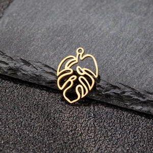 Detailed macro view of golden hollow monstera leaf pendants on a black stone surface