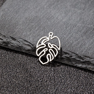 Polished silver stainless steel monstera leaf pendant with hollow design on dark stone