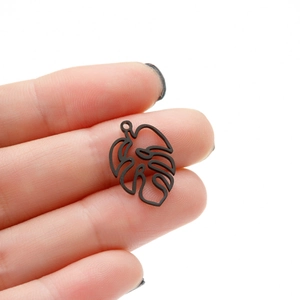 Macro shot of matte black monstera leaf pendant with hollow vein details for DIY jewelry