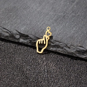 Golden stainless steel heart gesture pendant displayed on a dark natural rock surface