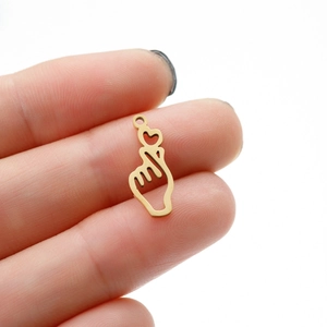 Macro shot of gold finger heart gesture pendant charm held between fingers for DIY jewelry