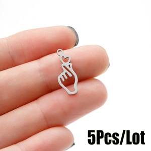 Close-up of five heart gesture steel pendants held on a fingertip for size reference