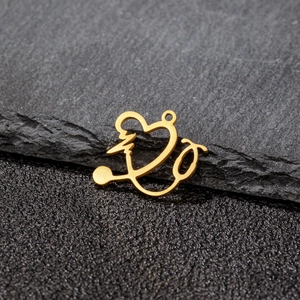 Golden stainless steel heart stethoscope pendant on a textured dark stone background