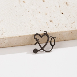 Macro shot of matte black stethoscope heart pendant on a textured stone surface