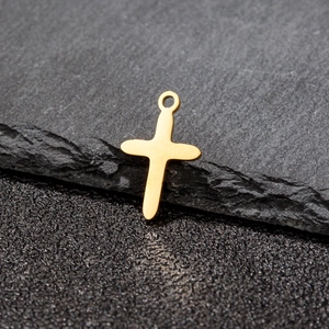 Minimalist gold plated stainless steel cross pendant on a textured black stone background